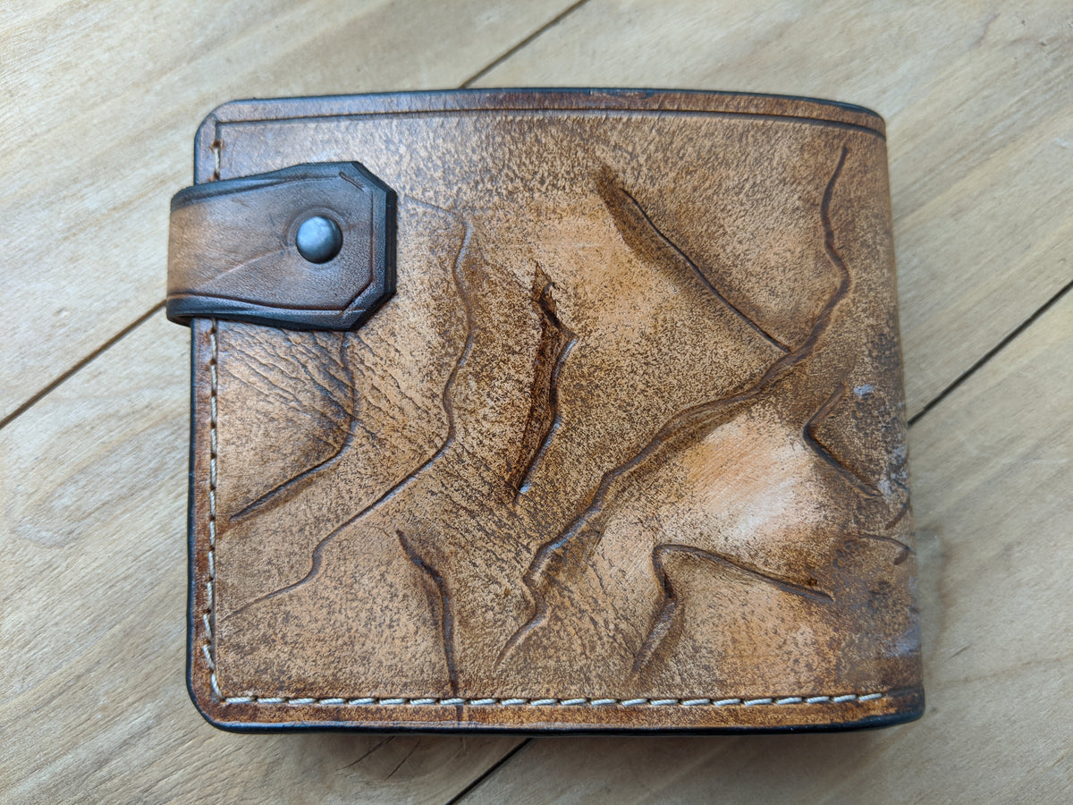 Handmade tooled leather bifold wallet featuring a grizzly bear design, ideal for bikers and hunters